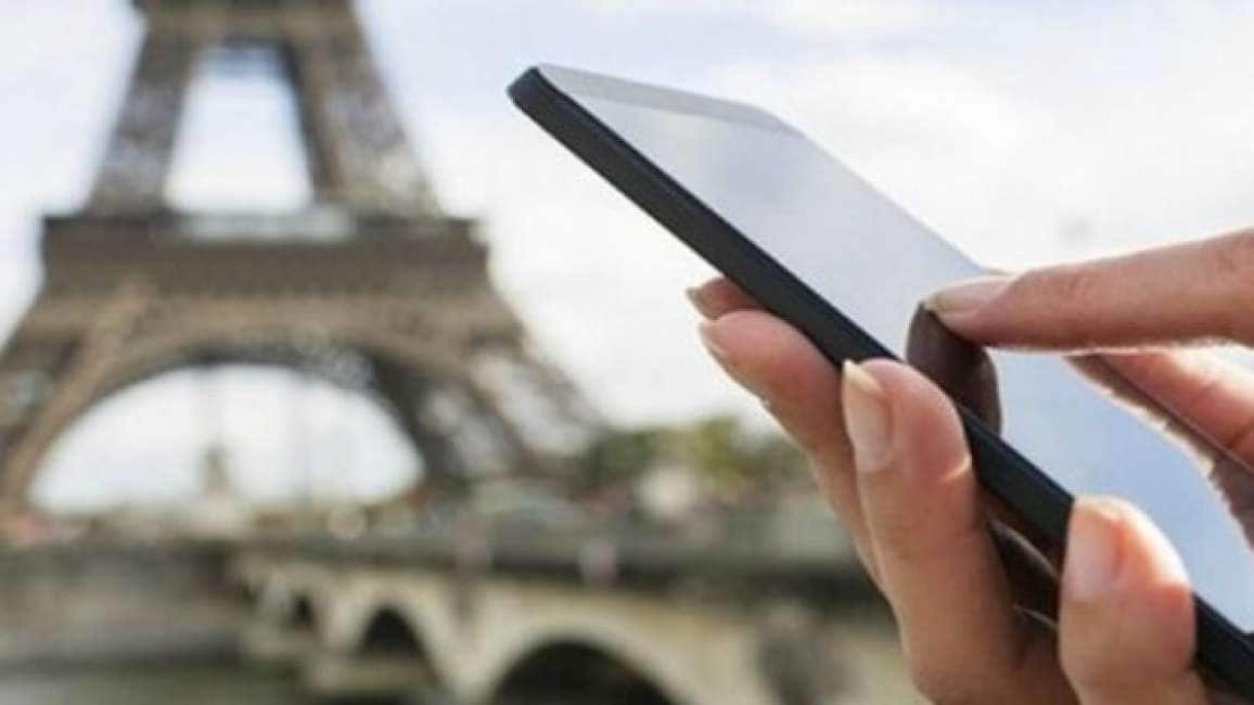 un telefonino tenuto in mano, sullo sfondo la torre Eiffel